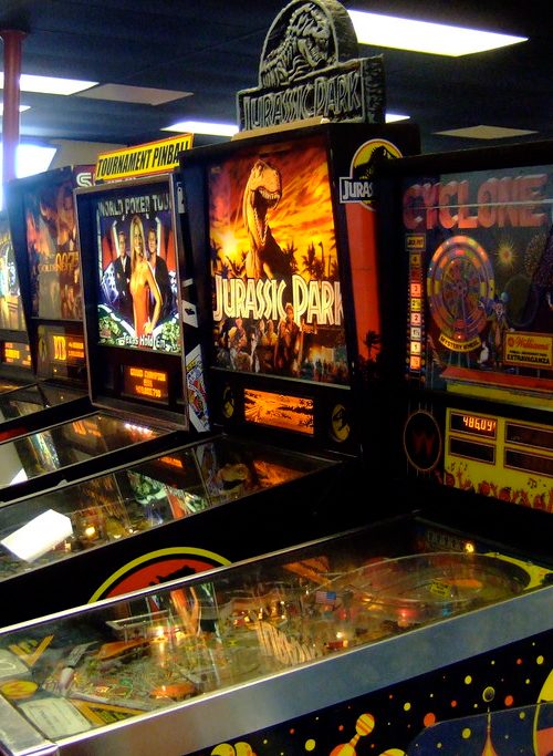 Jurassic Park pinball machine with its T-Rex backglass and cabinet topper
